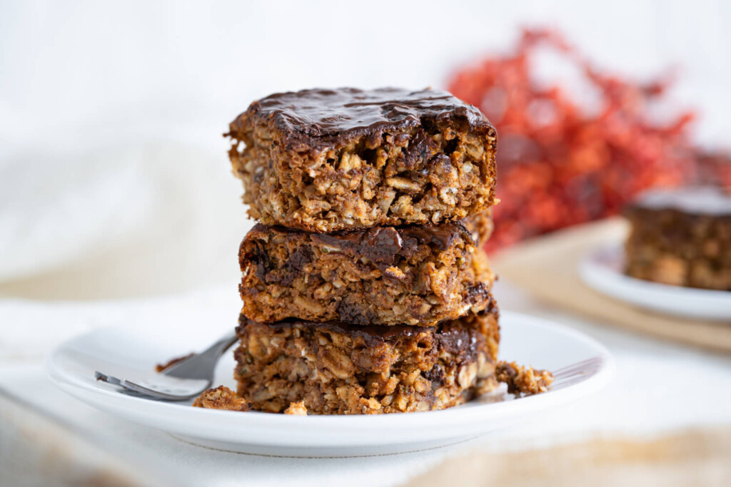 Stack of three pumpkin chocolate protein bars on a white plate.