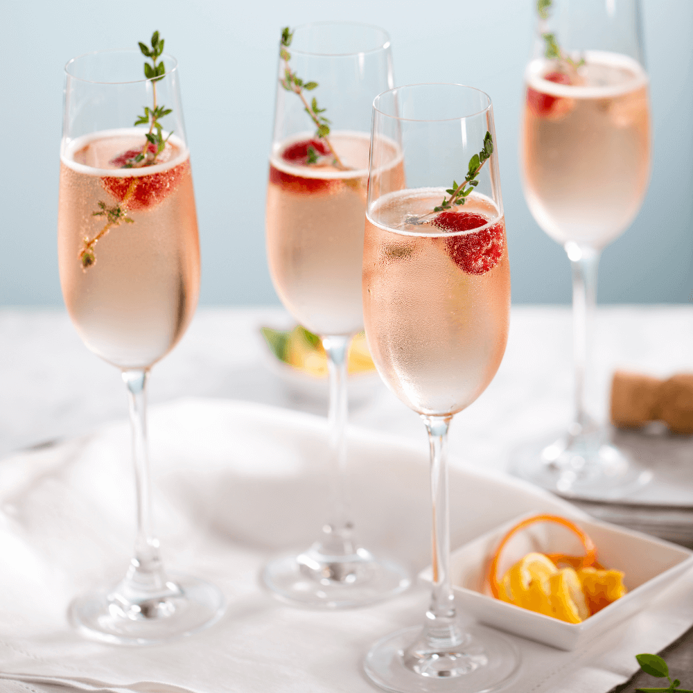 Flutes of pink rose champagne garnished with red raspberries and green thyme make for a festive cocktail gathering.