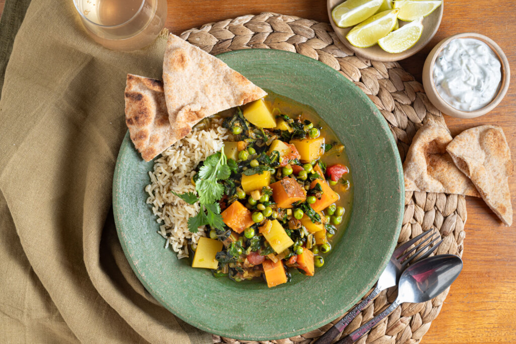 Overhead view of green bowl with curried vegetable stew. A healthy recipe made with root vegetables