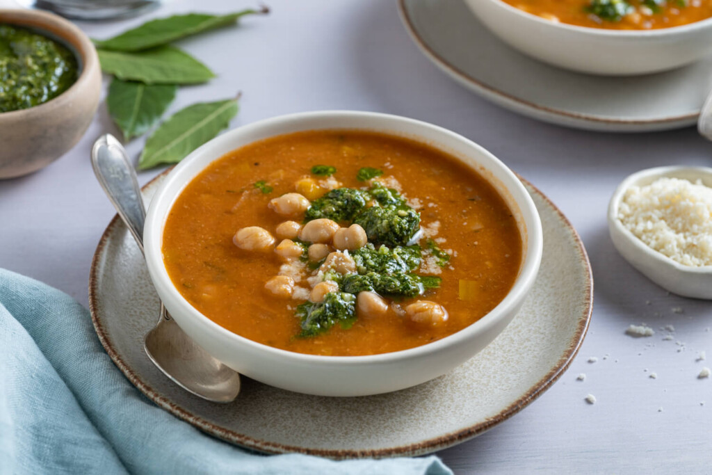 Plate with bowl of hearty chickpea soup garnished with basil pesto