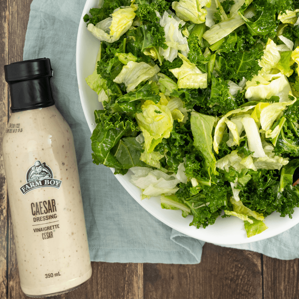 Overhead image of bowl of chopped lettuce greens beside bottle of Farm Boy Caesar Dressing