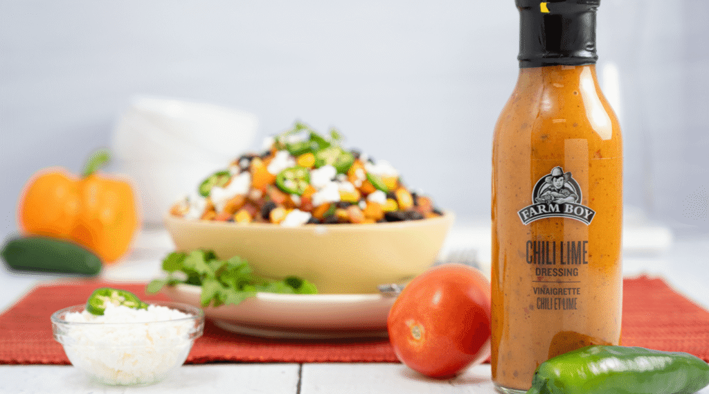 Bottle of Farm Boy Chili Lime Dressing in foreground with bean salad in background